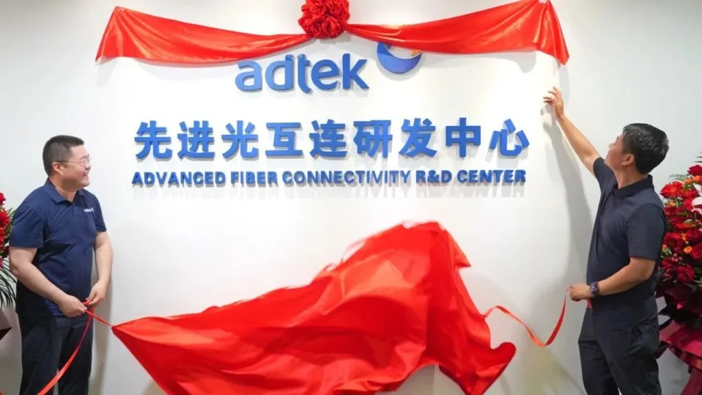 Two men unveiling red ribbon at ADTEK Advanced Fiber Connectivity R&D Center ceremony