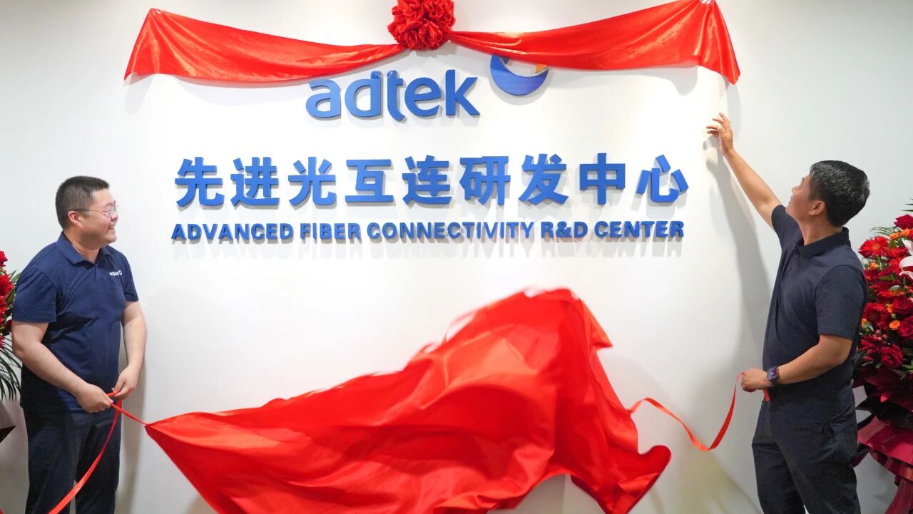 Two men unveiling red ribbon at ADTEK Advanced Fiber Connectivity R&D Center ceremony